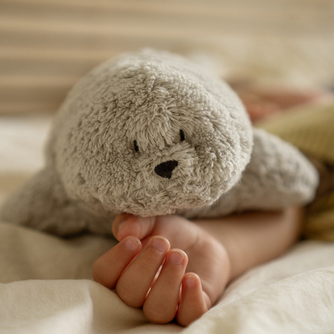 Moonie Robbe grau liegt auf Babys Hand