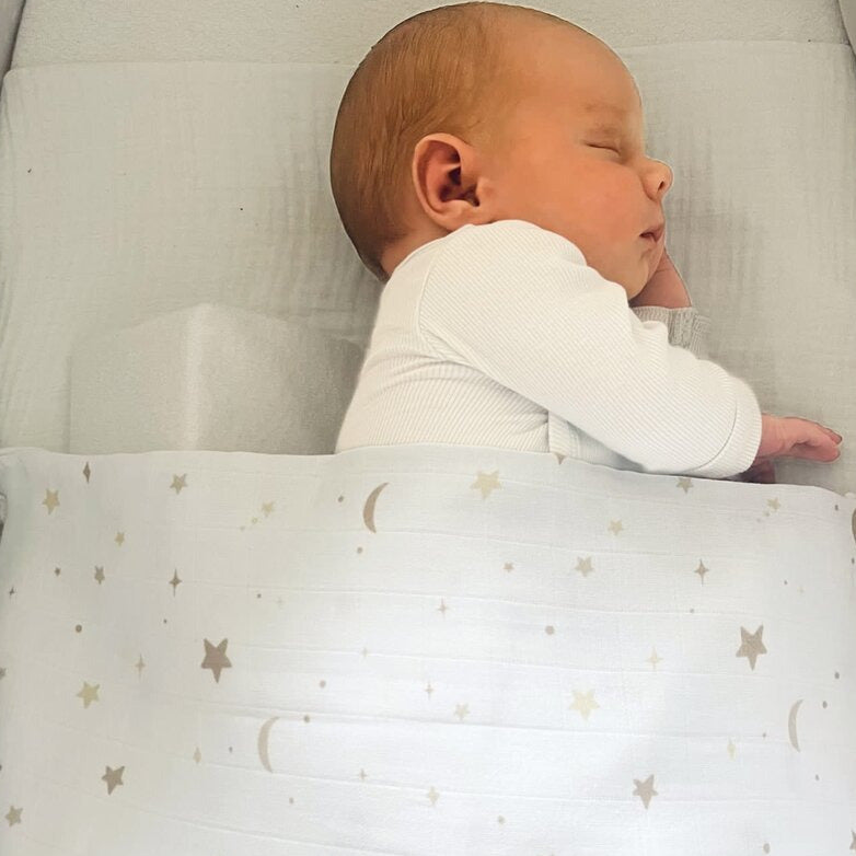 Baby zugedeckt mit einem Pucktuch Swaddle weiß mit Mond & Sternen von Poetree Kids