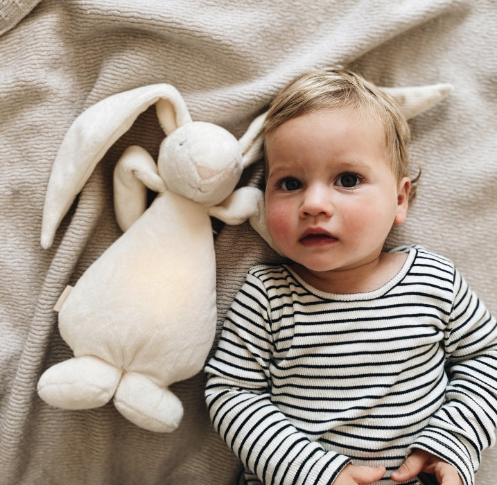 Moonie Hase cream liegt neben dem Kind
