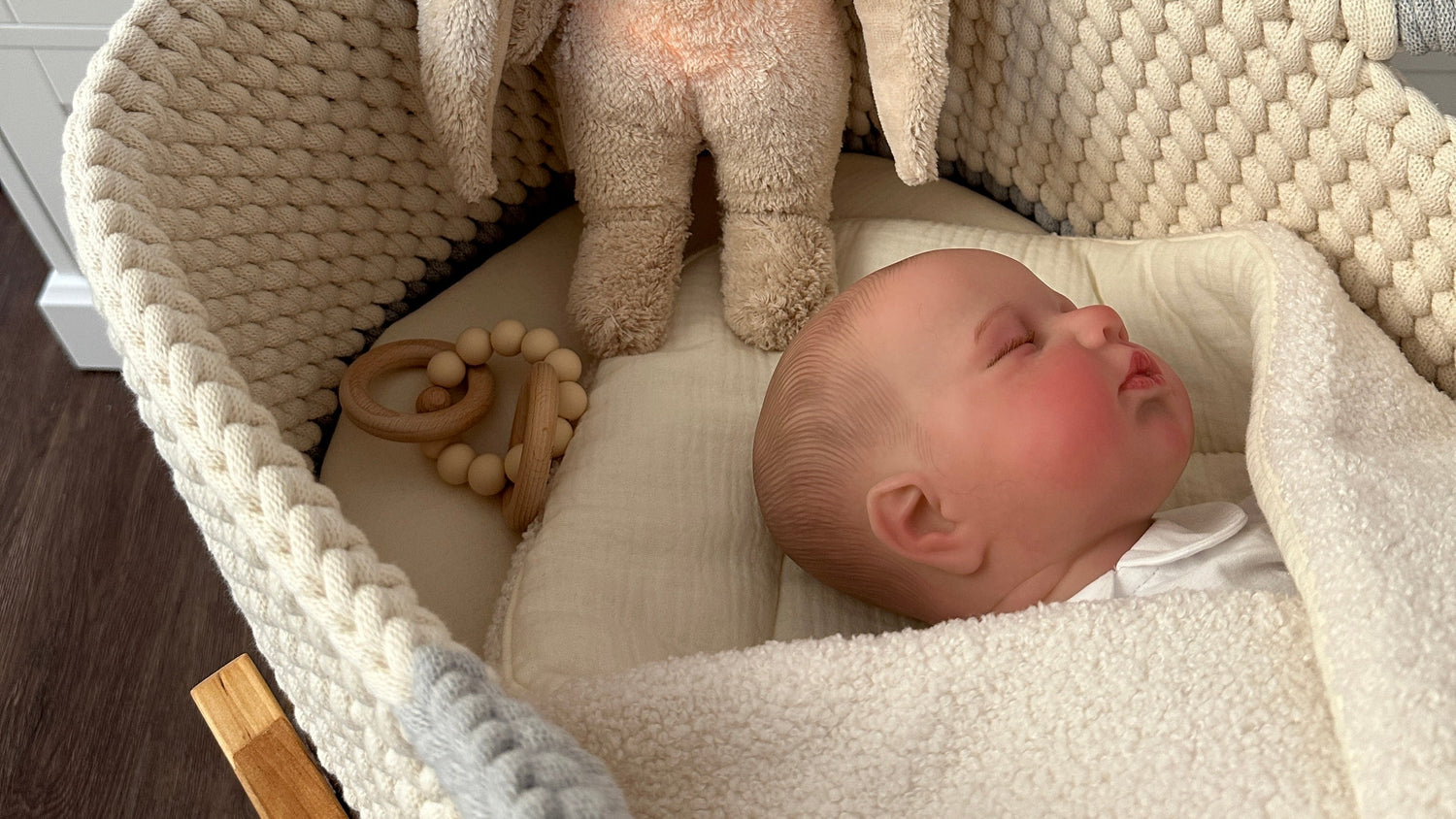 Baby schläft im Moseskorb in Begletung des Moonie Hasen
