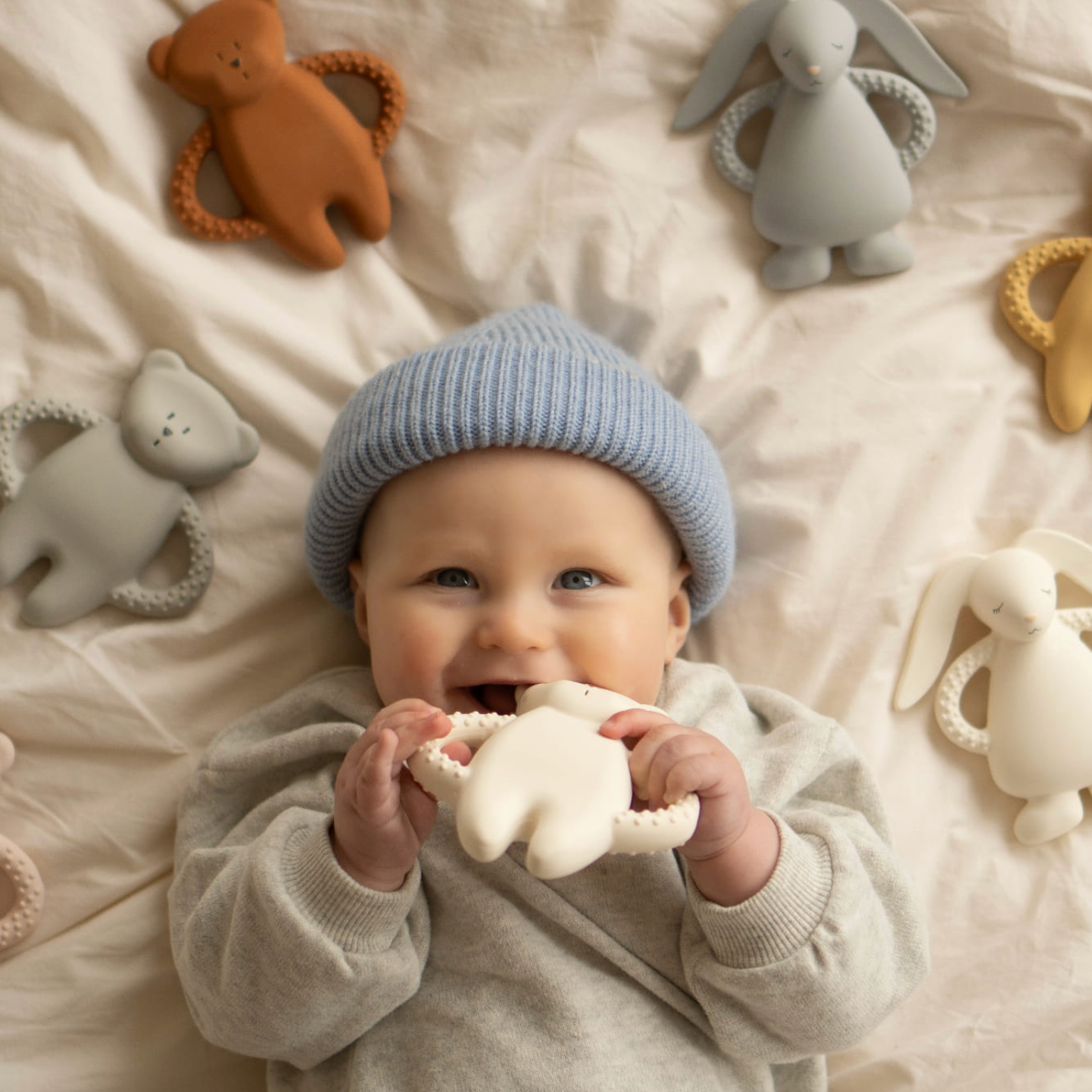 Baby hält einen Moonie Beißring und lächelt