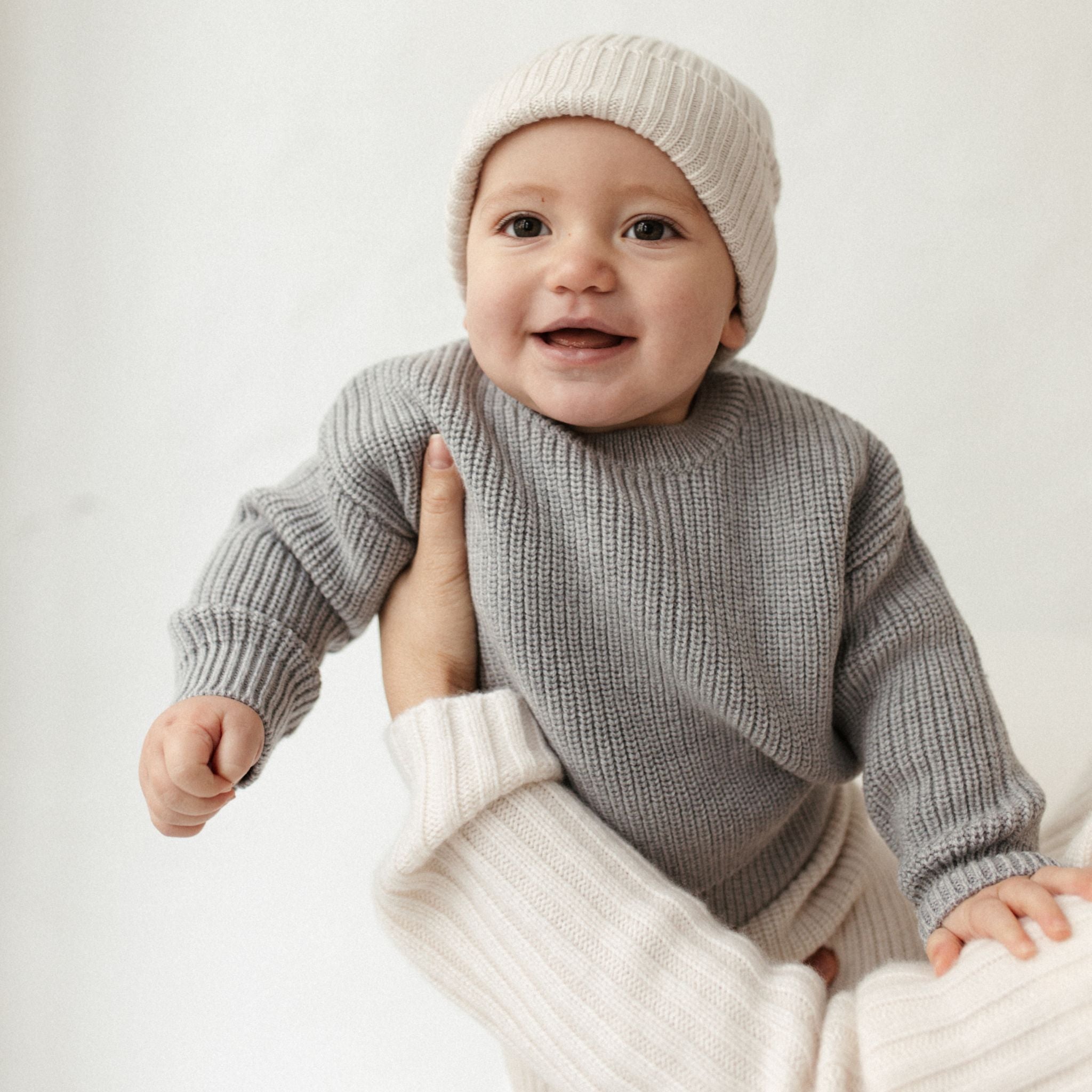 Baby trägt Pullover aus Merinowolle grau