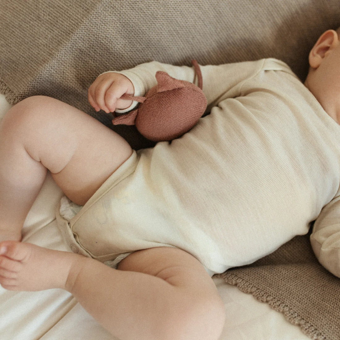 Baby trägt Body aus Merinowolle in Creme von Lille Toni